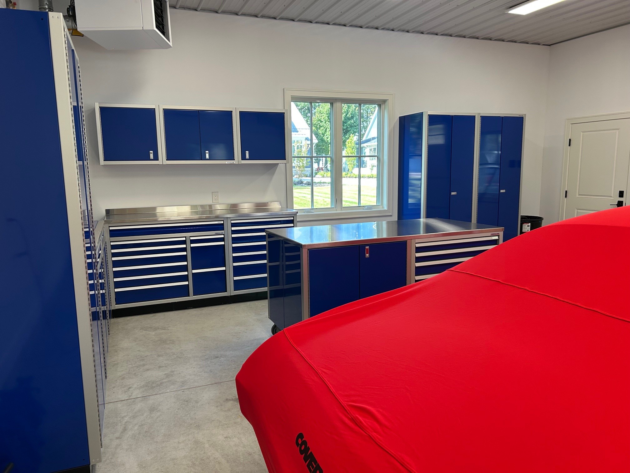 A car garage with Moduline aluminum cabinets in Moduline Blue, including a mobile center island